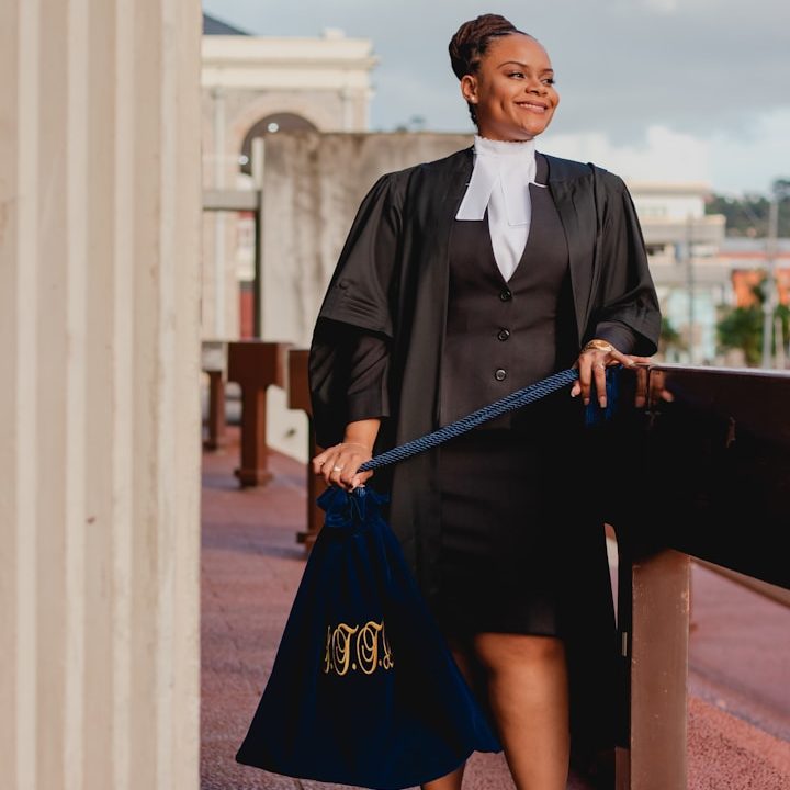 BU für Kammerberufe Frau in akademischer Robe hält einen Abschlussbeutel auf einem Balkon zur Berufsunfähigkeitsversicherung