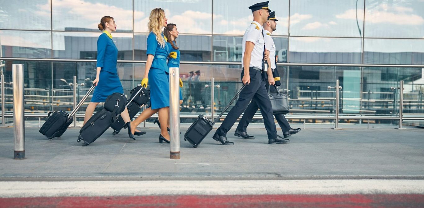 BU für Piloten und Flugpersonal Fünf Personen in Uniform mit Gepäck gehen am Flughafen entlang. BU für Piloten und Flugpersonal