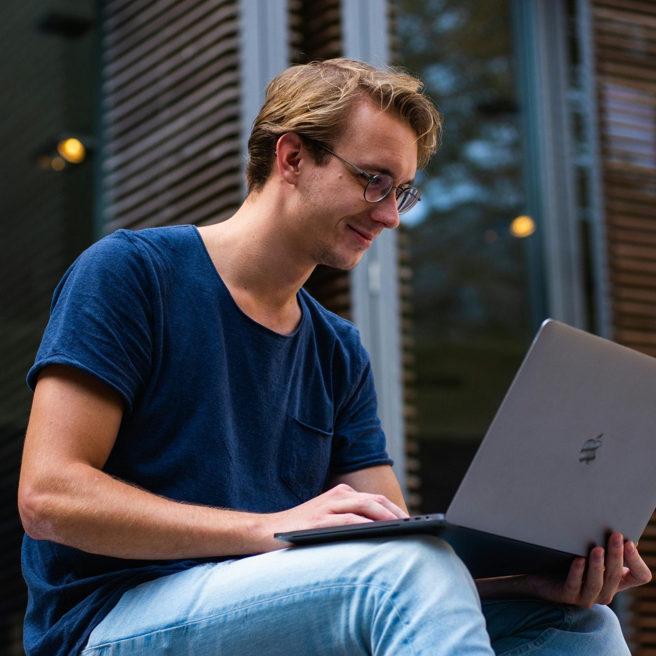 Junger Mann sitzt draußen und arbeitet konzentriert an einem Laptop.