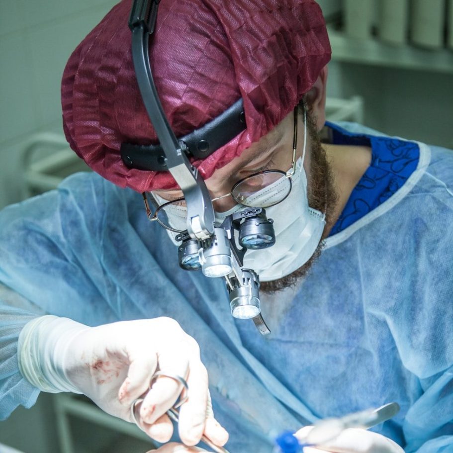 BU für Ärzte & Mediziner Chirurg in Schutzkleidung, konzentriert bei einem medizinischen Eingriff zur Berufsunfähigkeitsversicherung