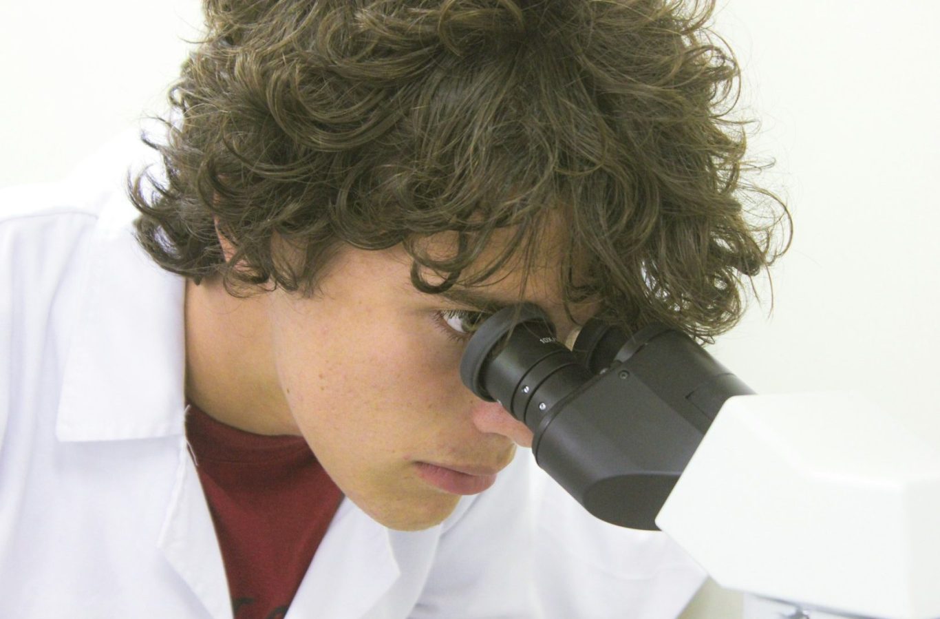 BU für MINT-Berufe Junger Wissenschaftler schaut durch ein Mikroskop in einem Labor. BU für MINT-Berufe