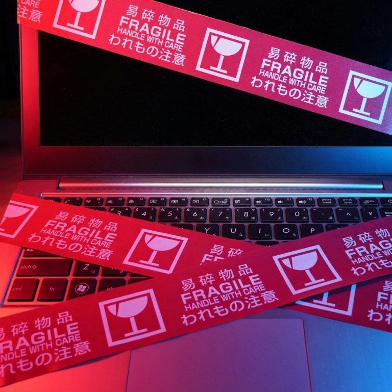 Laptop-Tastatur mit roten Aufklebern, die "Fragile" anzeigen.