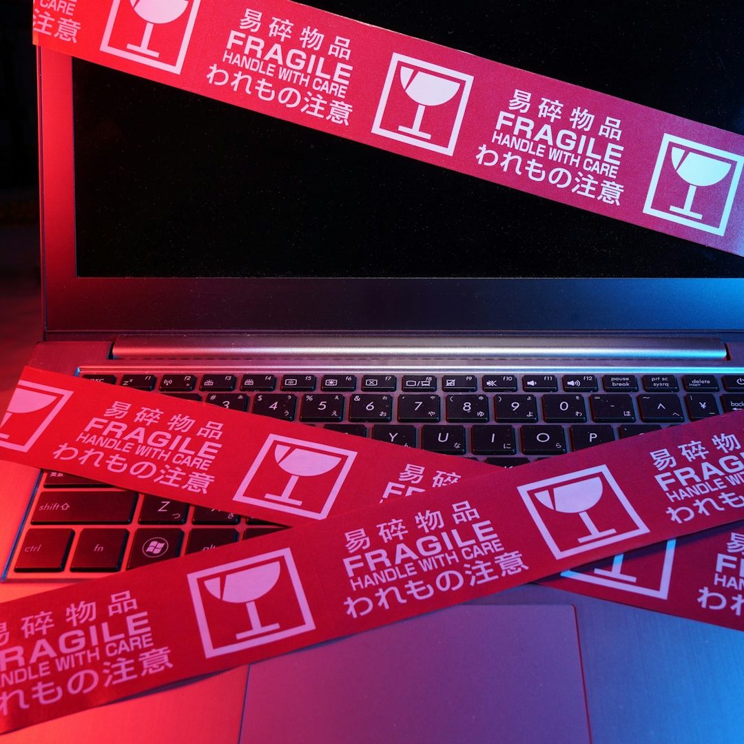 Laptop-Tastatur mit roten Aufklebern, die "Fragile" anzeigen.