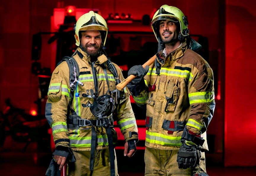 BU für Feierwehrberufe Zwei Feuerwehrleute in Schutzkleidung stehen vor einem Feuerwehrfahrzeug. BU für Feierwehrberufe