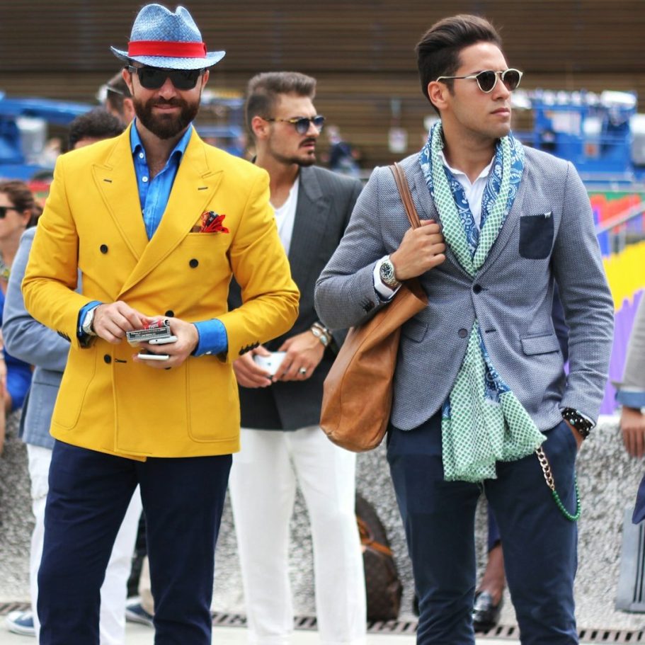 Zwei stilvoll gekleidete Männer, einer in gelbem Blazer, der andere in grauem Anzug.