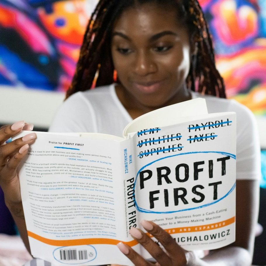 Frau mit Dreadlocks liest das Buch "Profit First".