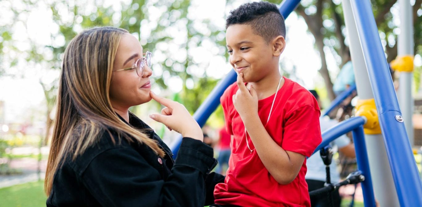 BU für Erzieher und soziale Berufe Eine Mutter und ihr Sohn spielen zusammen auf einem Spielplatz, beide lächeln. BU für Erzieher und soziale Berufe