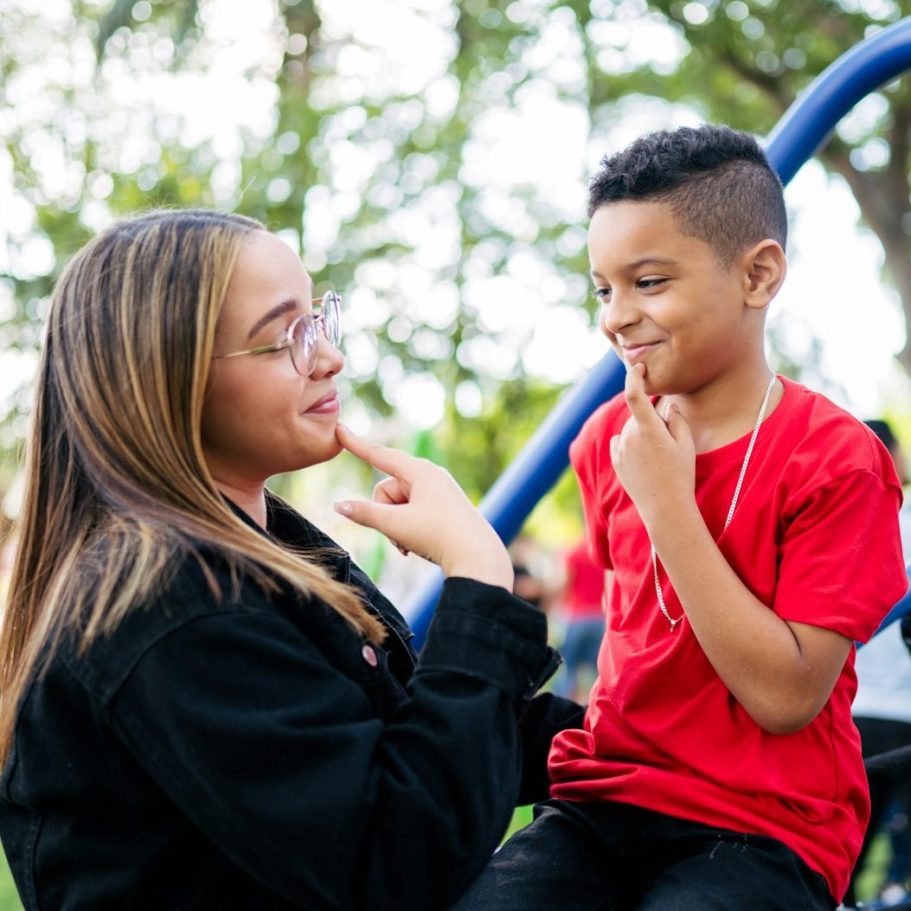 BU für Erzieher & Soziale Berufe Eine Frau und ein Junge spielen und lachen in einem Park zur Berufsunfähigkeitsversicherung