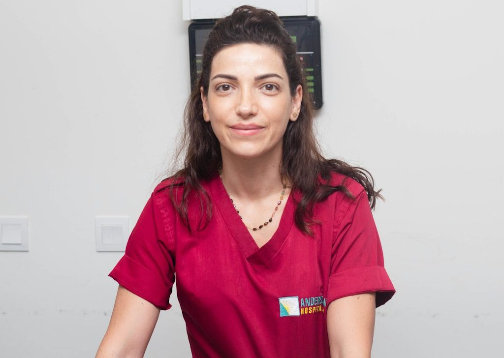 BU für Heil- und Pflegeberufe Frau in rotem Laborkittel steht vor einer medizinischen Geräteeinheit. BU für Heil- und Pflegeberufe