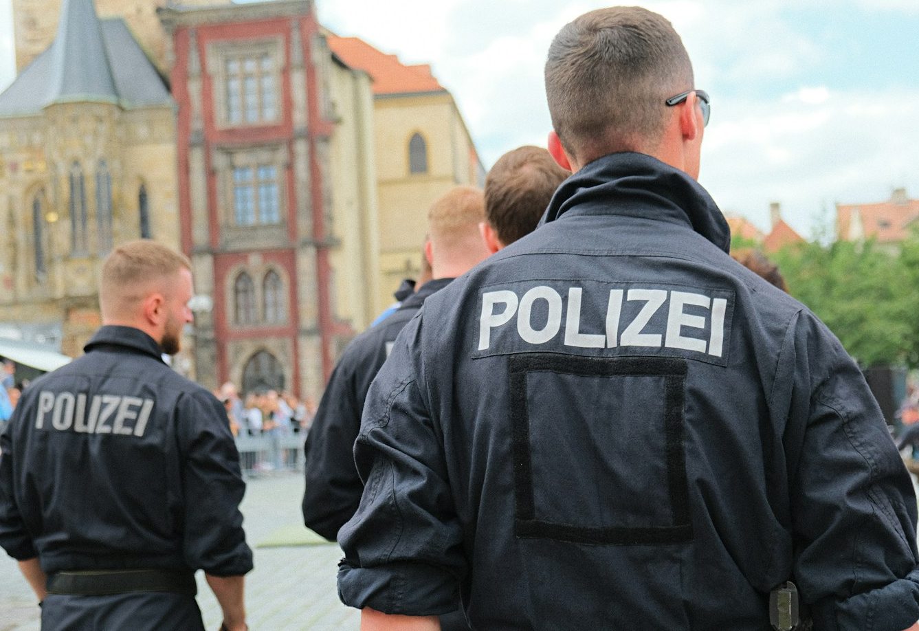 Polizisten in Uniform stehen mit dem Rücken zur Kamera auf einem Platz. BU für Polizisten