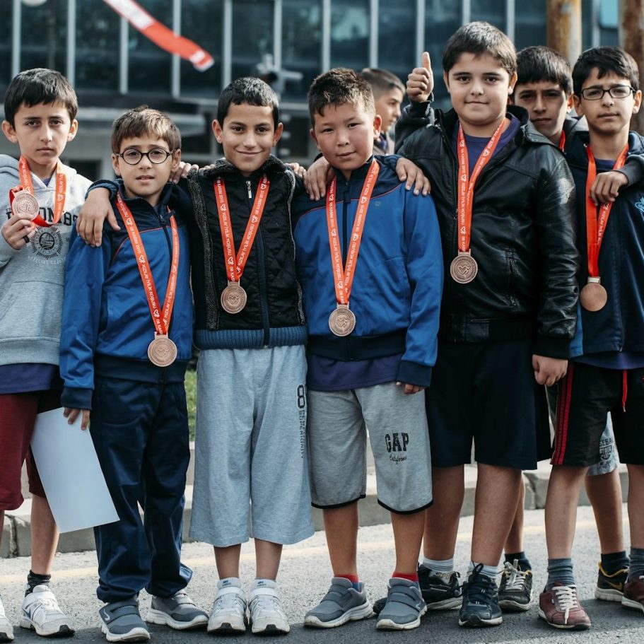 Gruppe von Jungen mit Medaillen, lächelnd und in Sportkleidung.