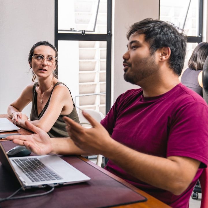 BU für Selbständige und Freiberufler Zwei Personen im Gespräch am Tisch, ein Laptop ist sichtbar zur Berufsunfähigkeitsversicherung