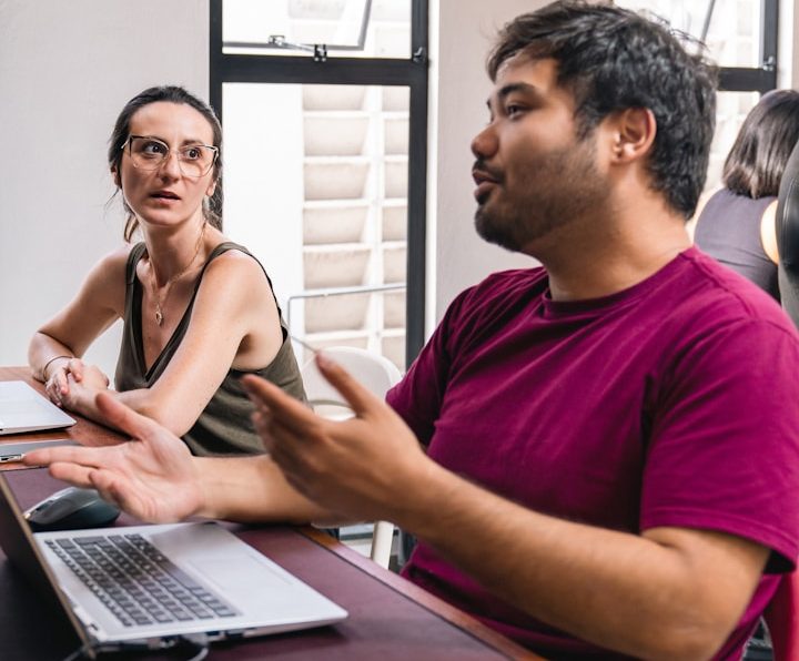 Zwei Personen im Gespräch, eine Frau und ein Mann, in einem hellen Raum und reden über BU für Selbstständige und Freiberufler